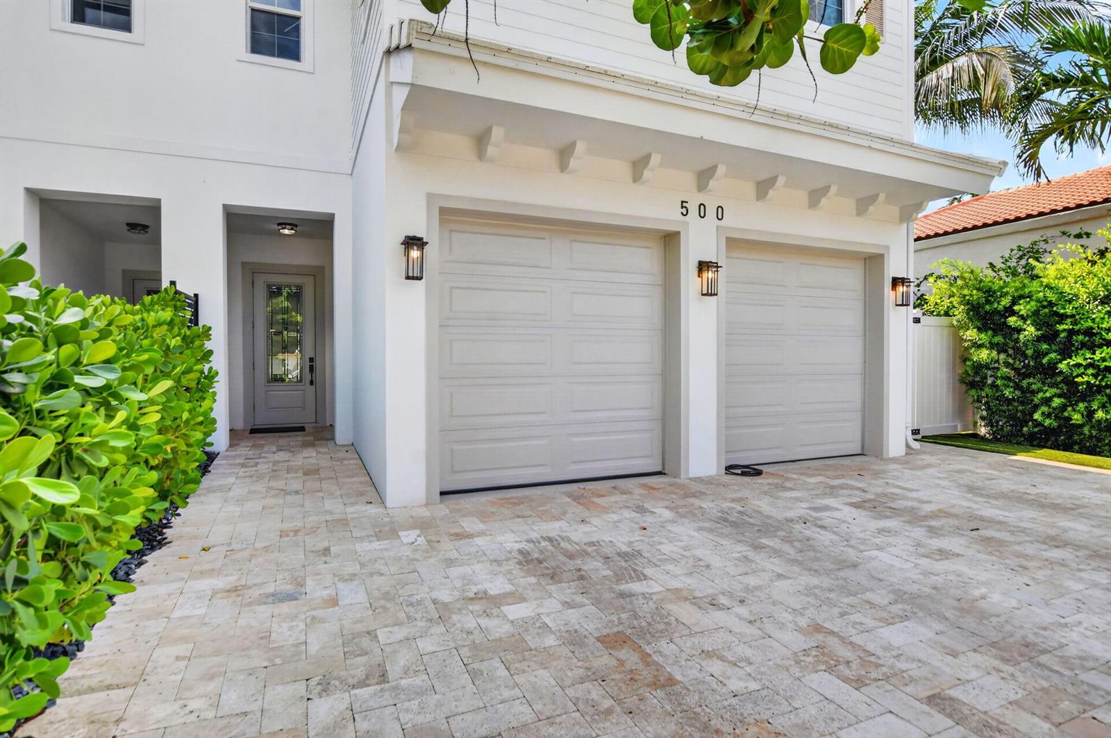 The exterior of a white house features a two-car garage and a stone-paved driveway — 500 NE Wavecrest Way, Boca Raton FL 33432, BOCA RATON, FL