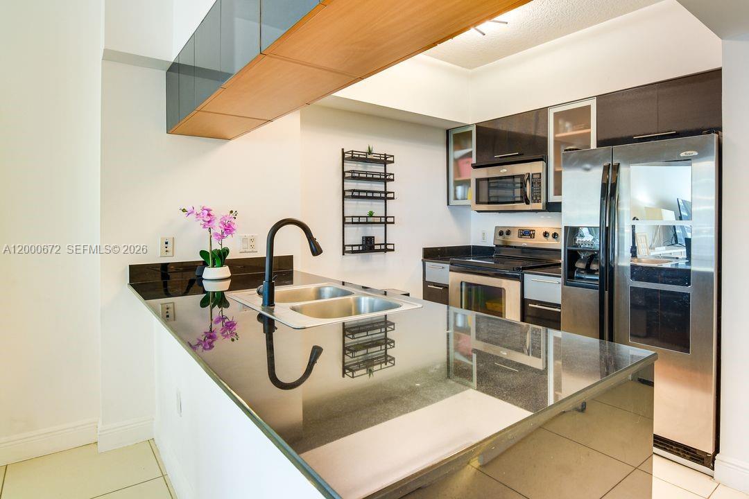 A kitchen features a black granite island with a sink, stainless steel appliances, and cabinets — 1750 N Bayshore Dr # 1909, Miami FL 33132, MIAMI, FL