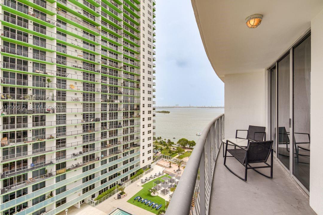 A balcony with two chairs overlooks a large apartment building and a body of water — 1750 N Bayshore Dr # 1909, Miami FL 33132, MIAMI, FL