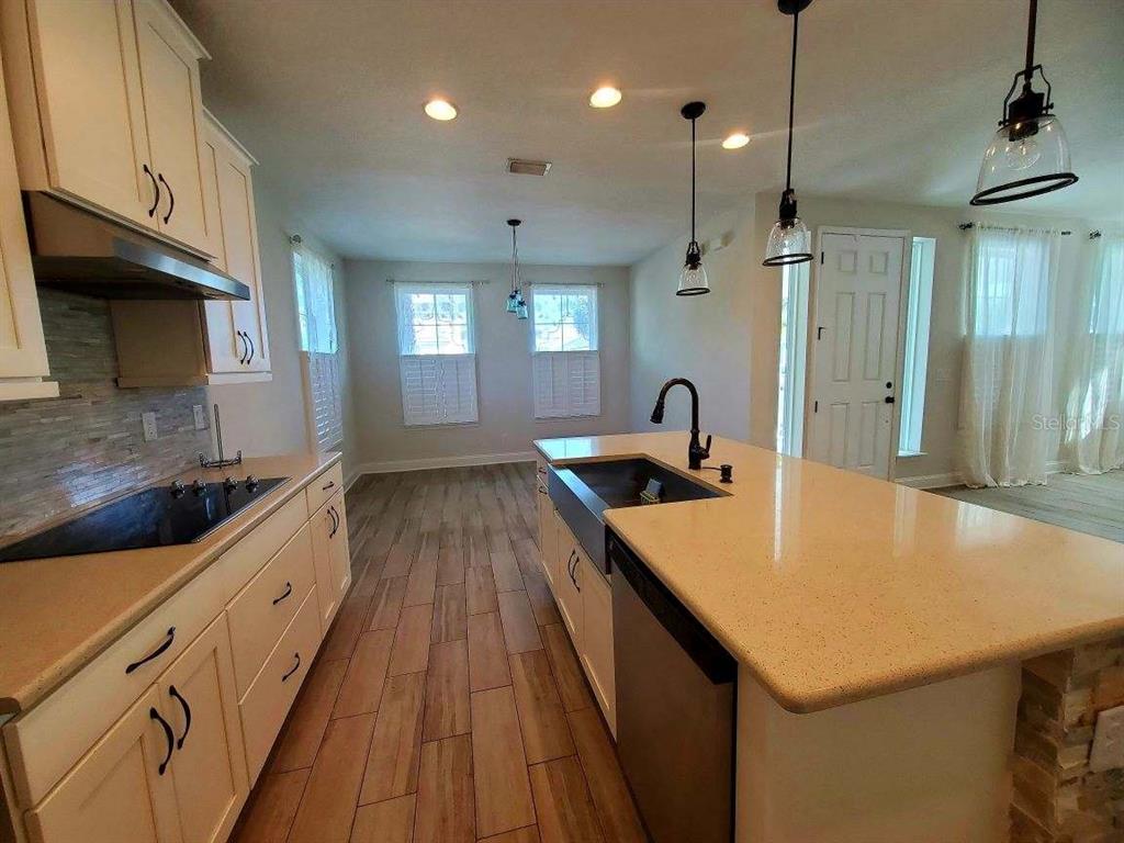 A kitchen features white cabinets, a large island with a farmhouse sink, and wood-look flooring — 37 SANDY BEACH WAY, PALM COAST, FL