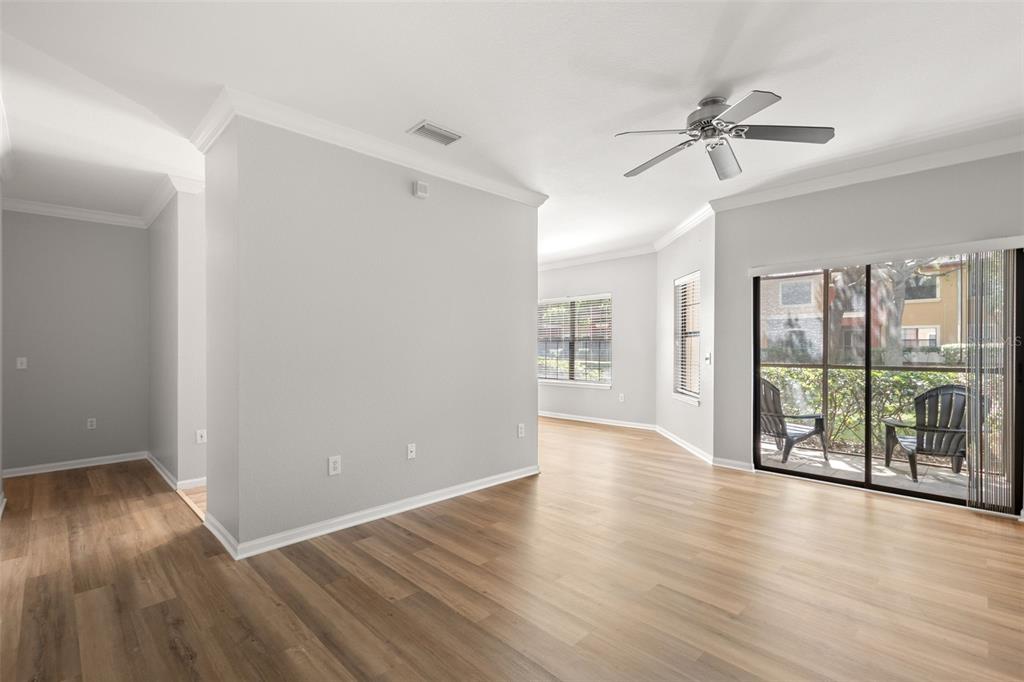 An empty living room features light gray walls, wood-look flooring, a ceiling fan, and sliding doors — 2200 TUSCANY TRACE UNIT 15, PALM HARBOR, FL