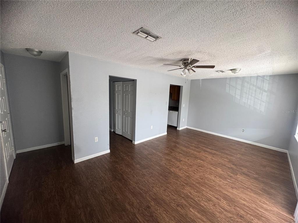 An interior view of a living room with gray walls, wood-look flooring, and a ceiling fan — 3544 PORTILLO ROAD UNIT 6, SPRING HILL, FL