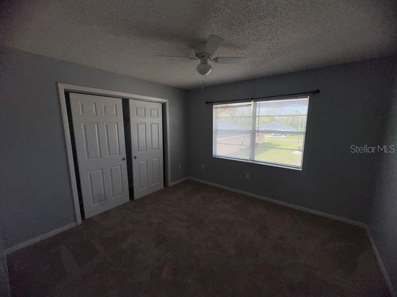 An empty bedroom features light gray walls, beige carpeting, a ceiling fan, and a closet — 3544 PORTILLO ROAD UNIT 6, SPRING HILL, FL
