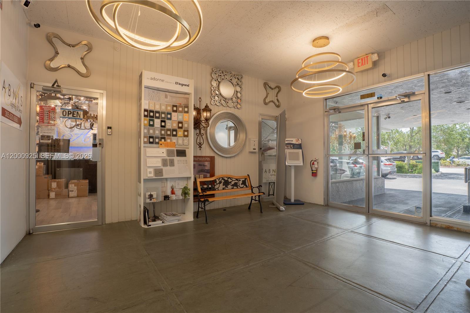A commercial showroom interior features modern circular light fixtures, a display wall, and glass doors — 6115 Miramar Pkwy, Miramar FL 33023, MIRAMAR, FL