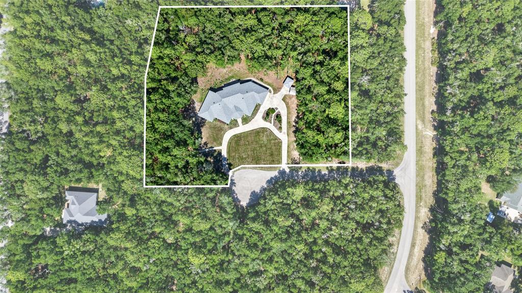 An aerial view shows a house with a driveway and lawn surrounded by dense forest — 7705 SW 186 AVENUE, DUNNELLON, FL