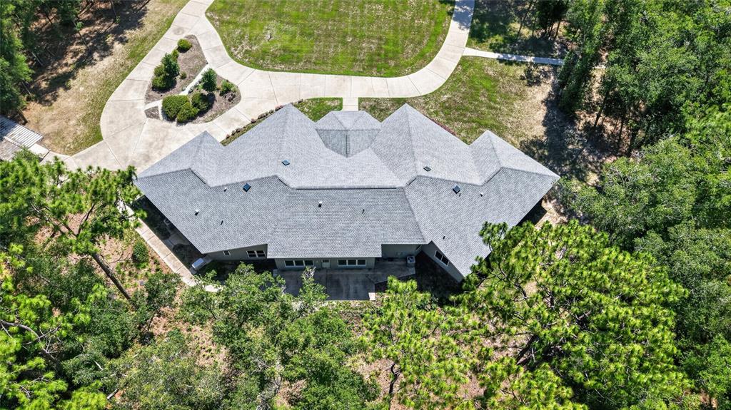 An aerial view shows a house with a gray shingled roof surrounded by trees — 7705 SW 186 AVENUE, DUNNELLON, FL