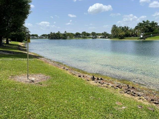 A grassy lawn slopes down to a lake with trees and houses in the distance — 13721 SW 84th St # G, Miami FL 33183, MIAMI, FL