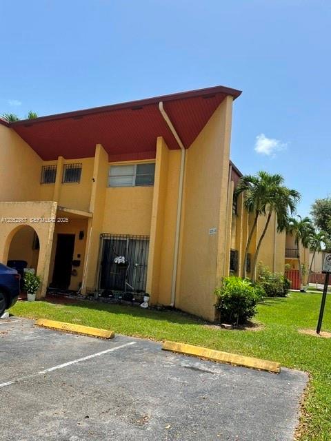 A two-story yellow apartment building features a dark roof and a parking lot foreground — 13721 SW 84th St # G, Miami FL 33183, MIAMI, FL