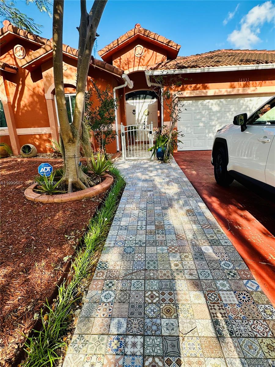 A single-story house with a paved driveway, two parked cars, and trees with Spanish moss — 14531 SW 160th Ct, Miami FL 33196, MIAMI, FL