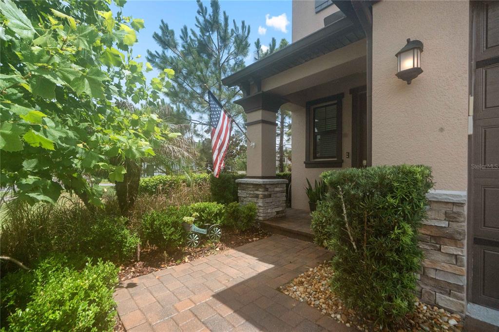 A brick walkway leads to the covered front porch of a house with stone accents — 4833 SAN MARTINO DRIVE, WESLEY CHAPEL, FL