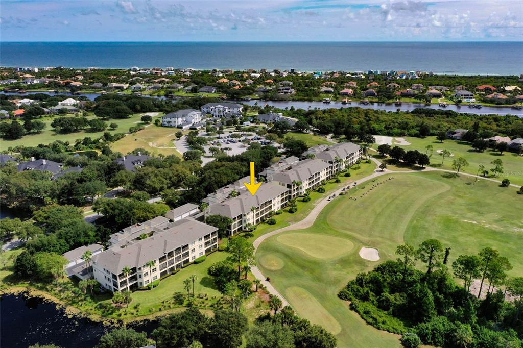 An aerial view shows a multi-story apartment complex situated next to a golf course — 200 RIVERFRONT DRIVE UNIT B303, PALM COAST, FL