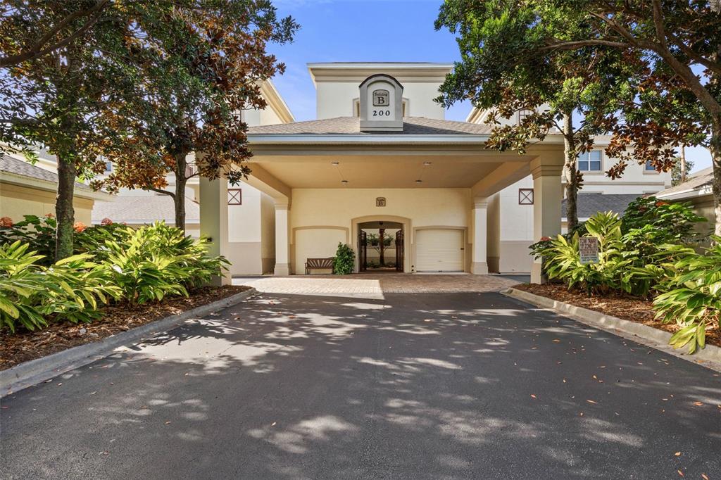 The exterior of a multi-story apartment building features a covered driveway entrance and lush landscaping — 200 RIVERFRONT DRIVE UNIT B303, PALM COAST, FL