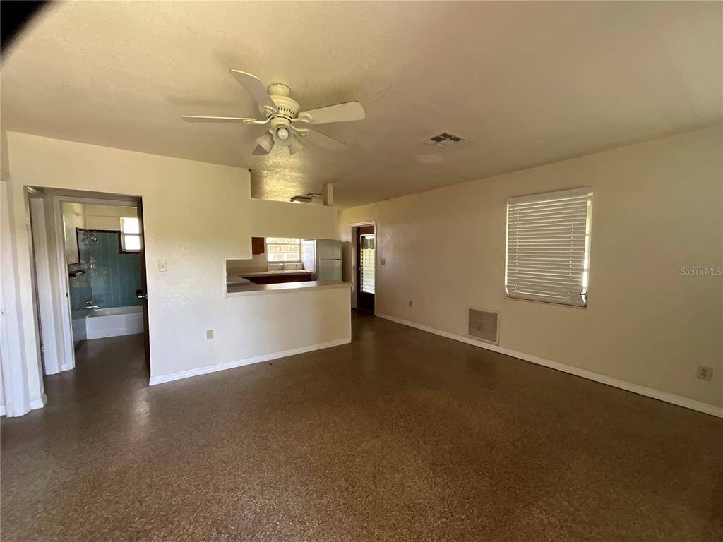 An open-concept living area features a ceiling fan, speckled flooring, and a view into the kitchen — 12455 SE 138TH AVENUE, OCKLAWAHA, FL