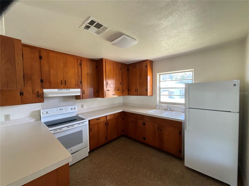 A kitchen features wood cabinets, white appliances, white countertops, and a window above the sink — 12455 SE 138TH AVENUE, OCKLAWAHA, FL