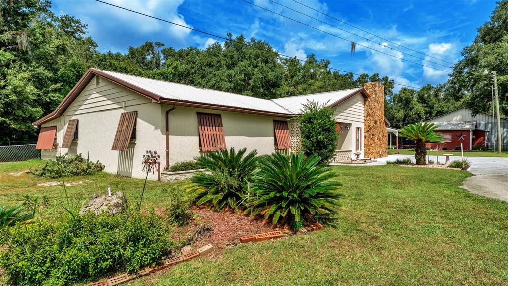 A single-story house with a stone chimney and metal roof sits on a grassy lot — 1301 LANIER ROAD, LAKELAND, FL