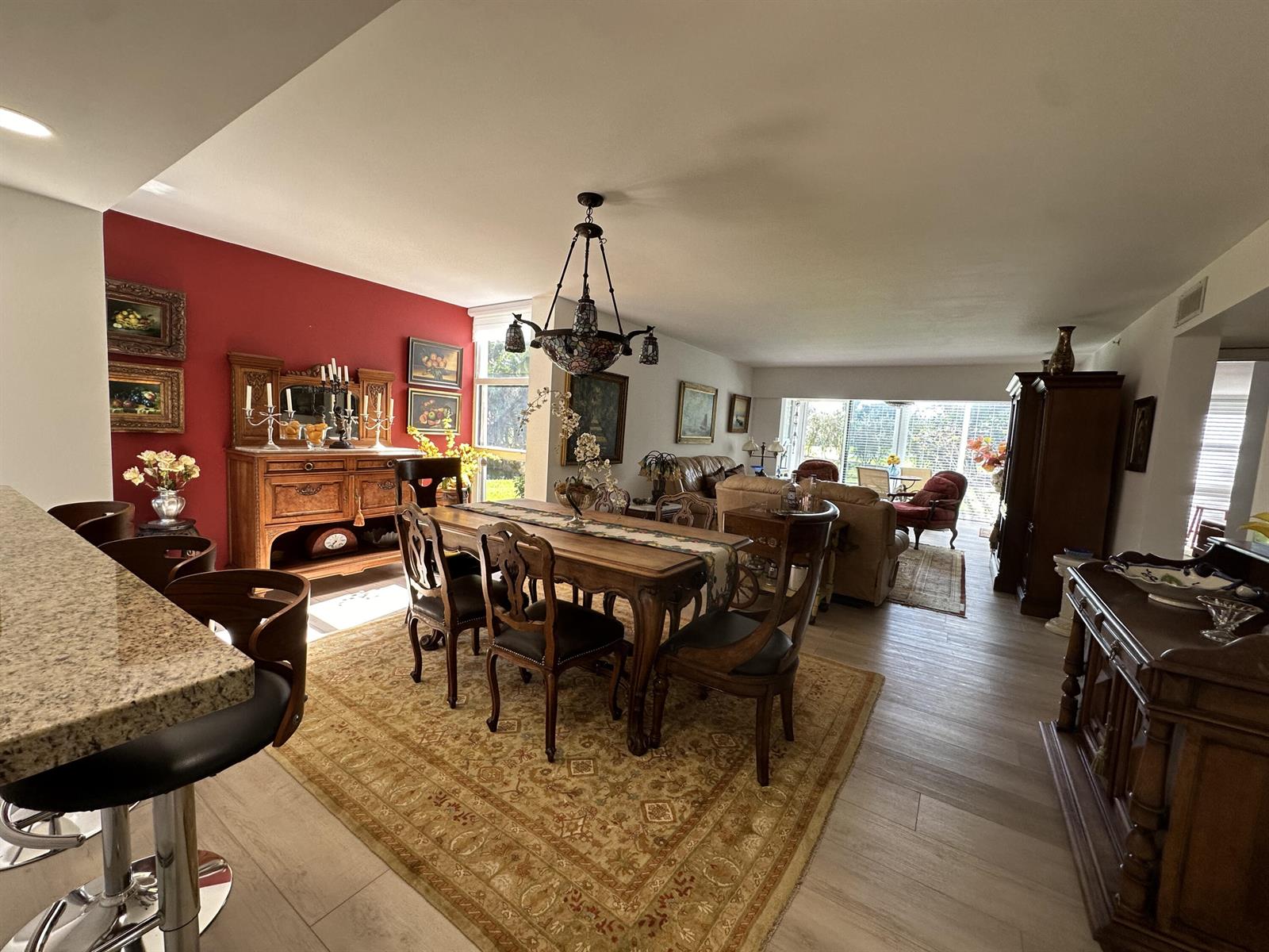 An open-concept dining and living area features a red accent wall, wood furniture, and flooring — 6662 Boca Del Mar Drive # 111, Boca Raton FL 33433, BOCA RATON, FL