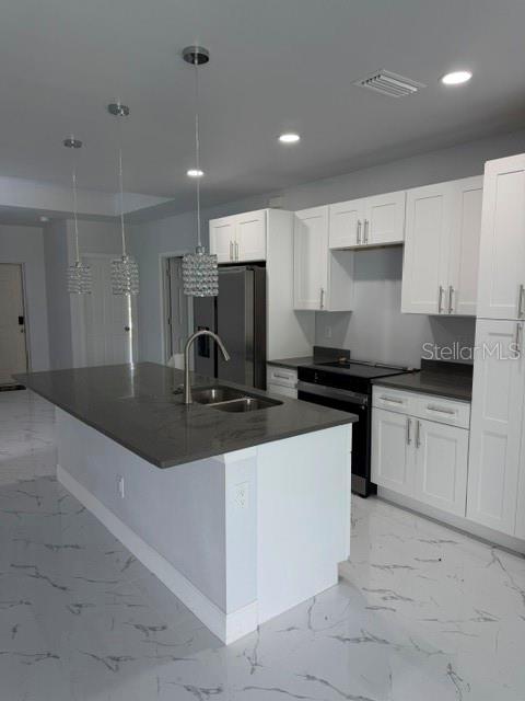 A modern kitchen features white cabinets, a dark gray island countertop, and marble-patterned tile flooring — 744/746 EISENHOWER BOULEVARD, LEHIGH ACRES, FL