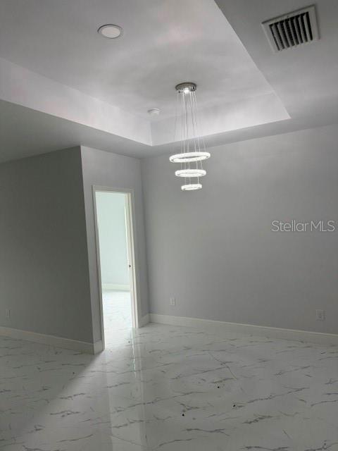 A room with white marble-patterned tile floors, gray walls, and a modern tiered chandelier — 744/746 EISENHOWER BOULEVARD, LEHIGH ACRES, FL