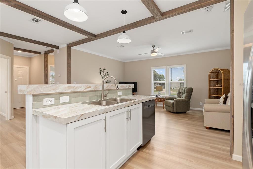 A kitchen island with a marble-look countertop overlooks a living area with light wood flooring — 6287 GREENFINCH ROAD, ENGLEWOOD, FL