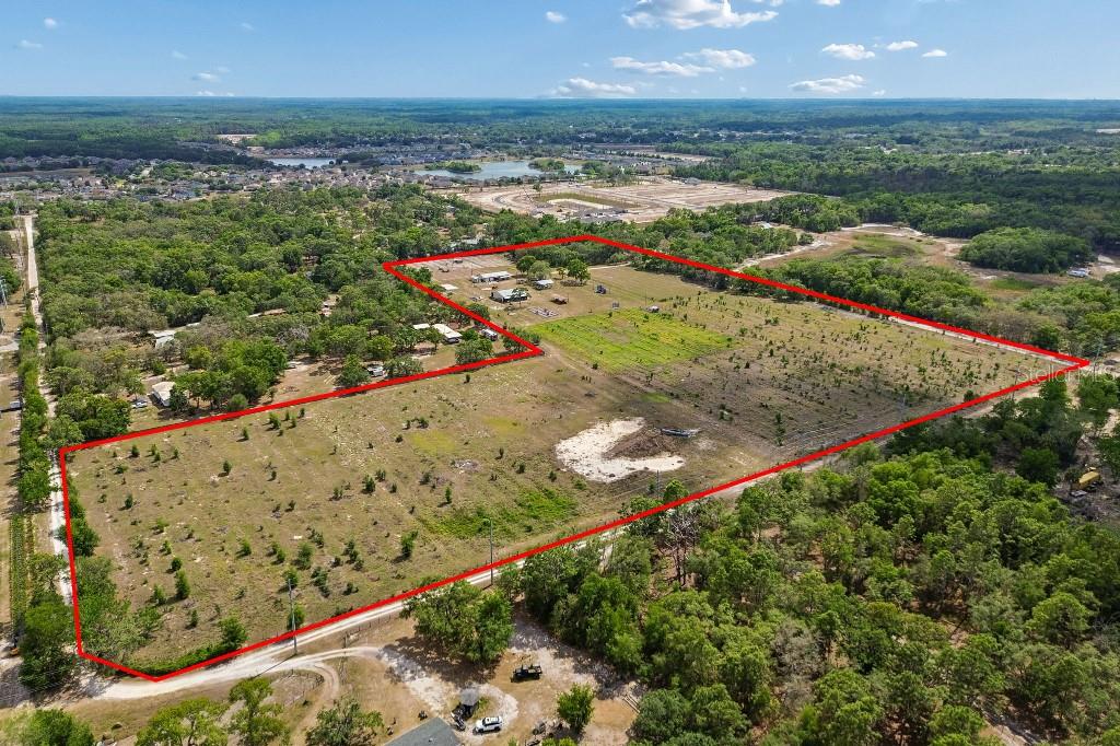 An aerial view shows a large, L-shaped plot of land outlined in red — 14320 FAMILY TRAIL, HUDSON, FL