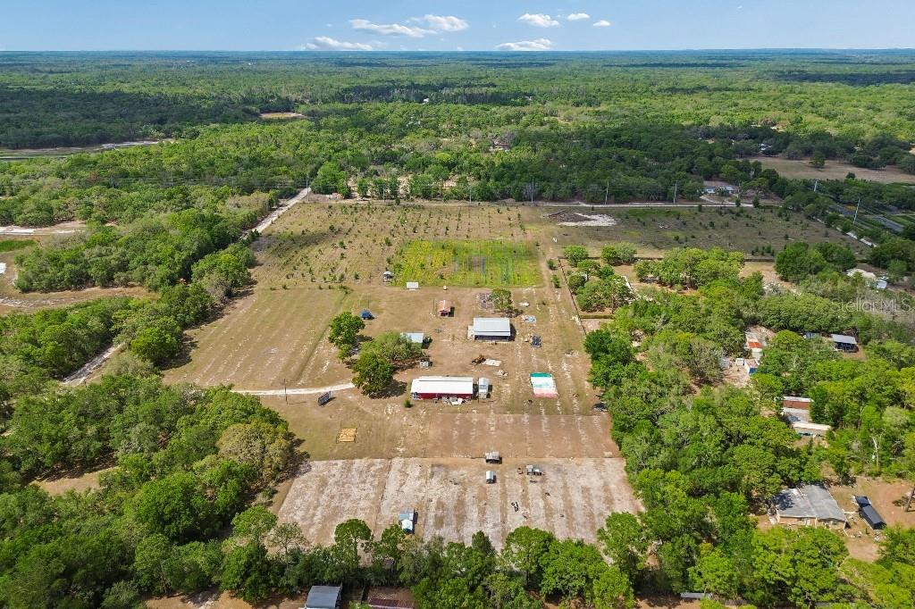 An aerial view shows a large rural property with several outbuildings and cleared agricultural land — 14320 FAMILY TRAIL, HUDSON, FL