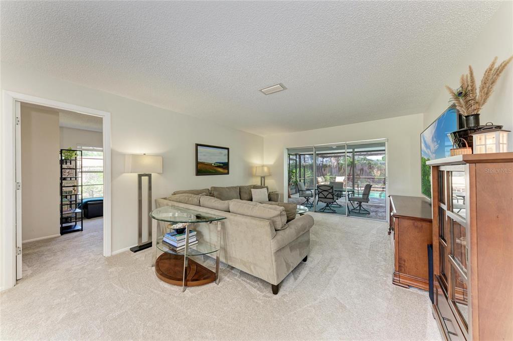 A living room features beige carpet, a sectional sofa, and sliding doors leading to a patio — 3980 LEMONWOOD DRIVE, SARASOTA, FL