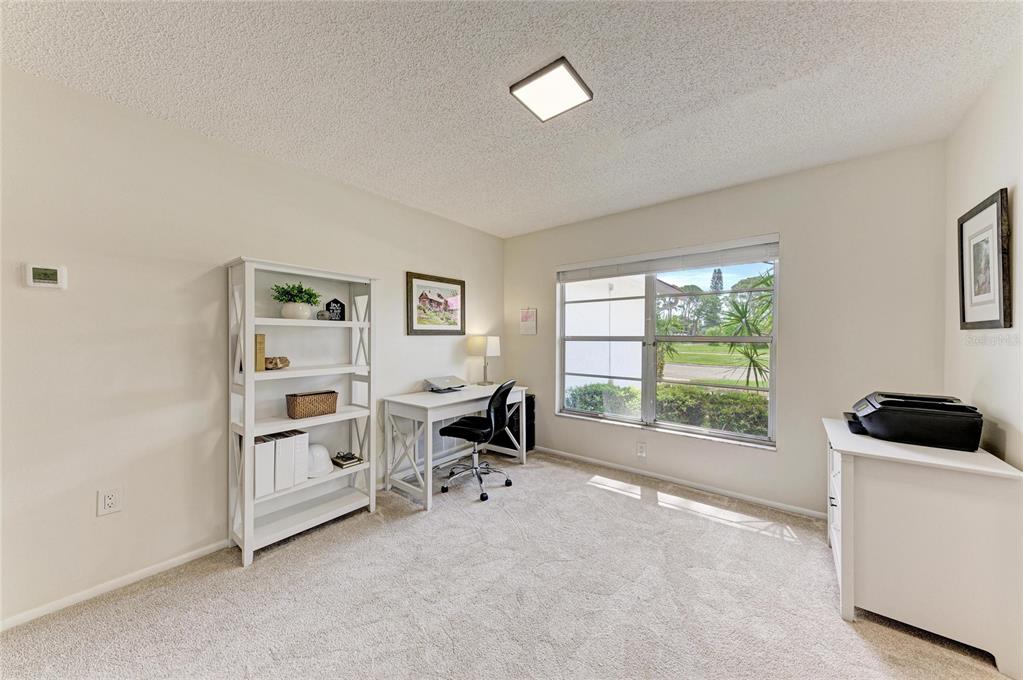A home office features a white desk, bookshelf, printer, carpeted flooring, and a large window — 3980 LEMONWOOD DRIVE, SARASOTA, FL