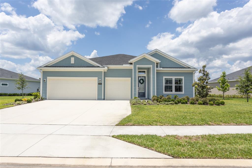 A single-story blue house features a three-car garage, a front porch, and a concrete driveway — 4171 ACOMA DRIVE, ORMOND BEACH, FL