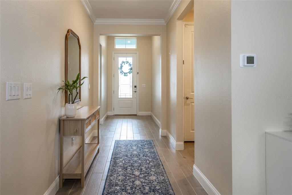 A hallway features light-colored tile flooring, a console table with a mirror, and a front door — 4171 ACOMA DRIVE, ORMOND BEACH, FL