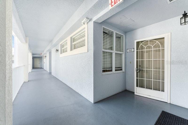 An exterior view of a building corridor with a white door and a window — 2001 BAL HARBOR BOULEVARD UNIT 2412, PUNTA GORDA, FL