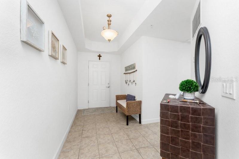 A tiled entryway features a wicker bench, a dark woven cabinet, and a round mirror — 2001 BAL HARBOR BOULEVARD UNIT 2412, PUNTA GORDA, FL