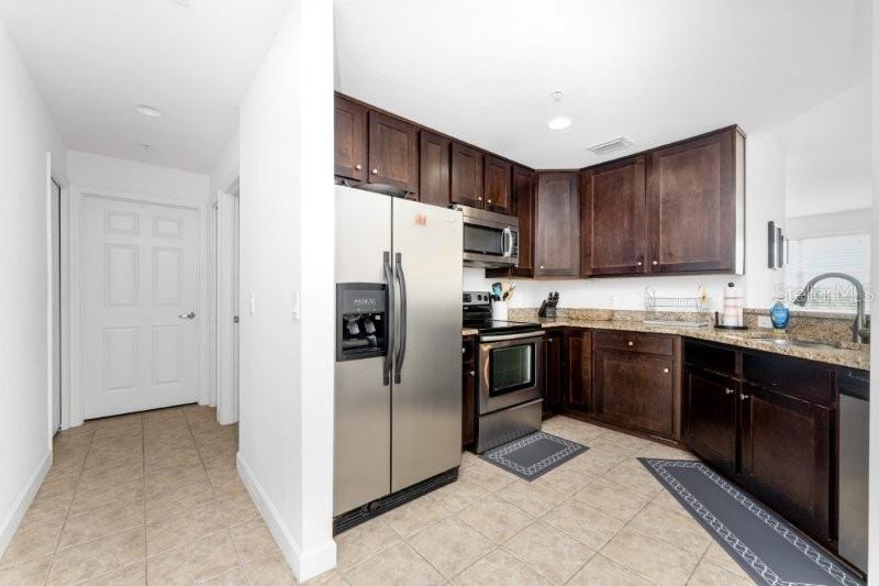 A kitchen features dark wood cabinets, stainless steel appliances, and beige tile flooring — 2001 BAL HARBOR BOULEVARD UNIT 2412, PUNTA GORDA, FL
