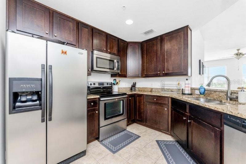 A kitchen features dark wood cabinets, stainless steel appliances, and granite countertops — 2001 BAL HARBOR BOULEVARD UNIT 2412, PUNTA GORDA, FL