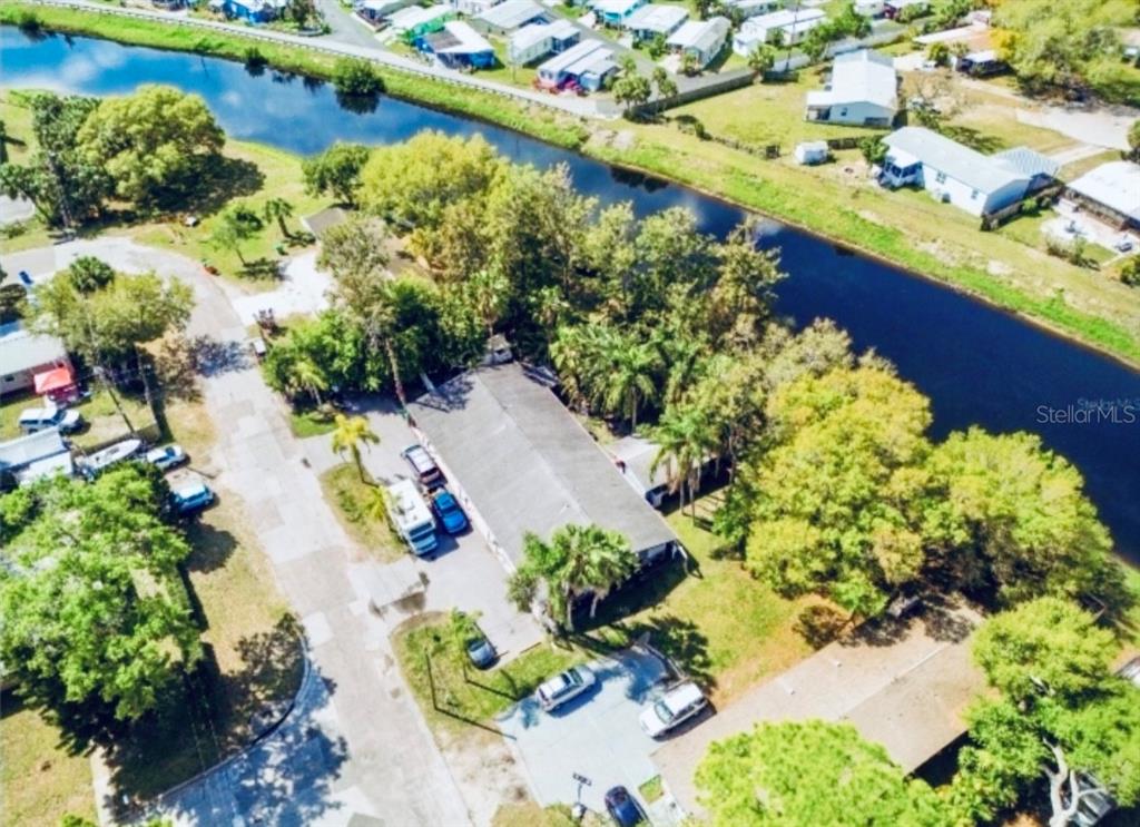 An aerial view shows a residential property with a long house beside a canal — 5050 74TH STREET N UNIT 1, ST PETERSBURG, FL