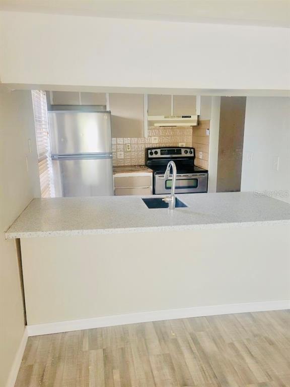 A kitchen features a breakfast bar, stainless steel refrigerator, and a black electric range — 5050 74TH STREET N UNIT 1, ST PETERSBURG, FL