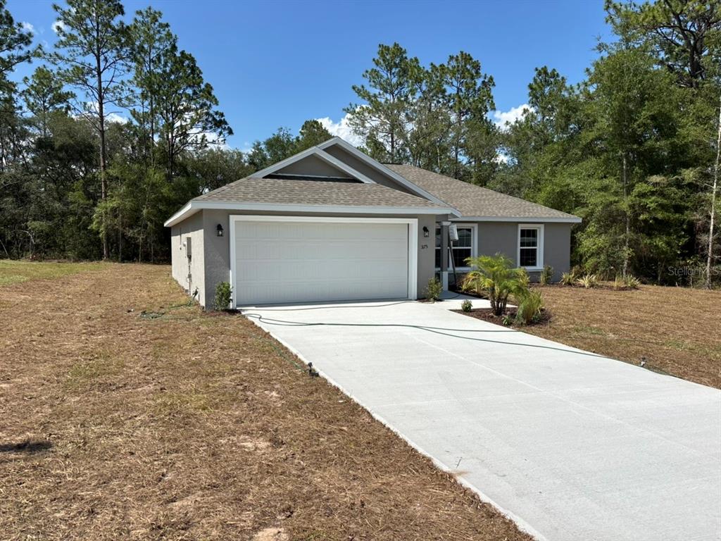 A single-story house with a white garage door, gray exterior, and a concrete driveway — 3175 W CAMILO DRIVE, DUNNELLON, FL
