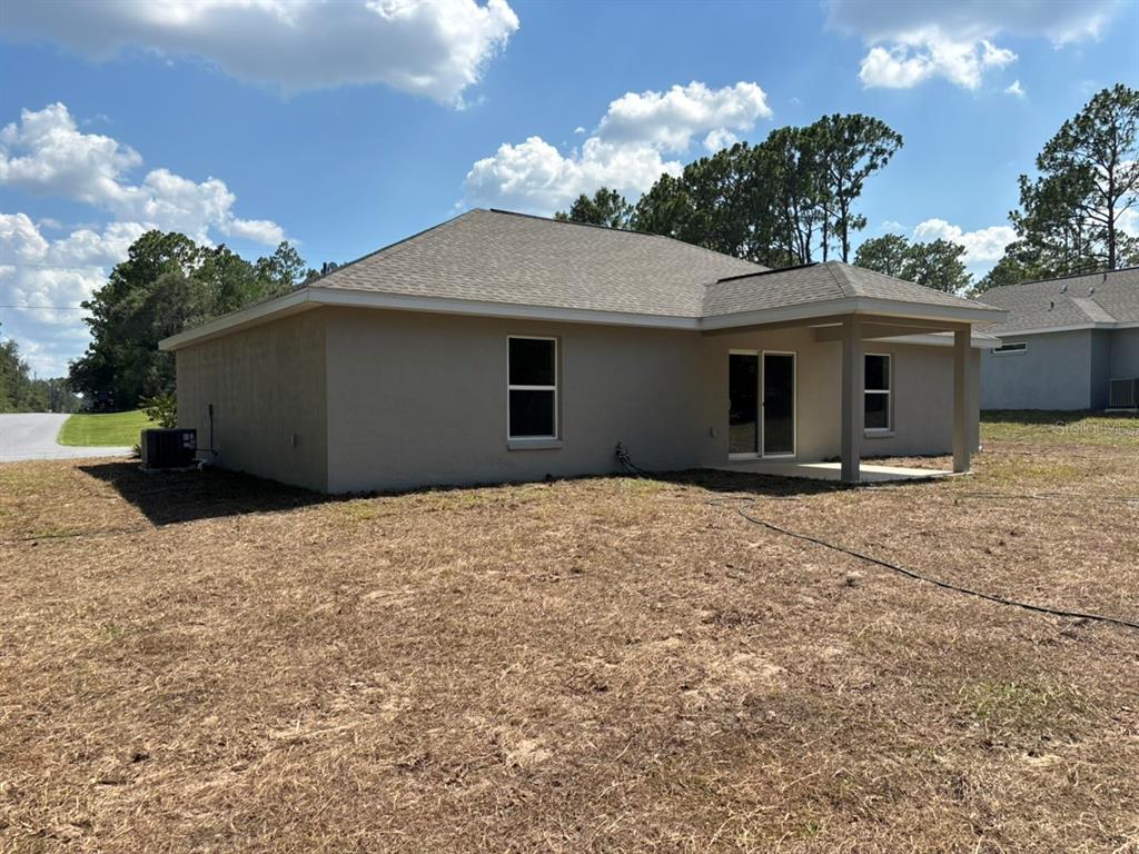 The exterior of a beige single-story house features a covered patio and a grassy yard — 3175 W CAMILO DRIVE, DUNNELLON, FL