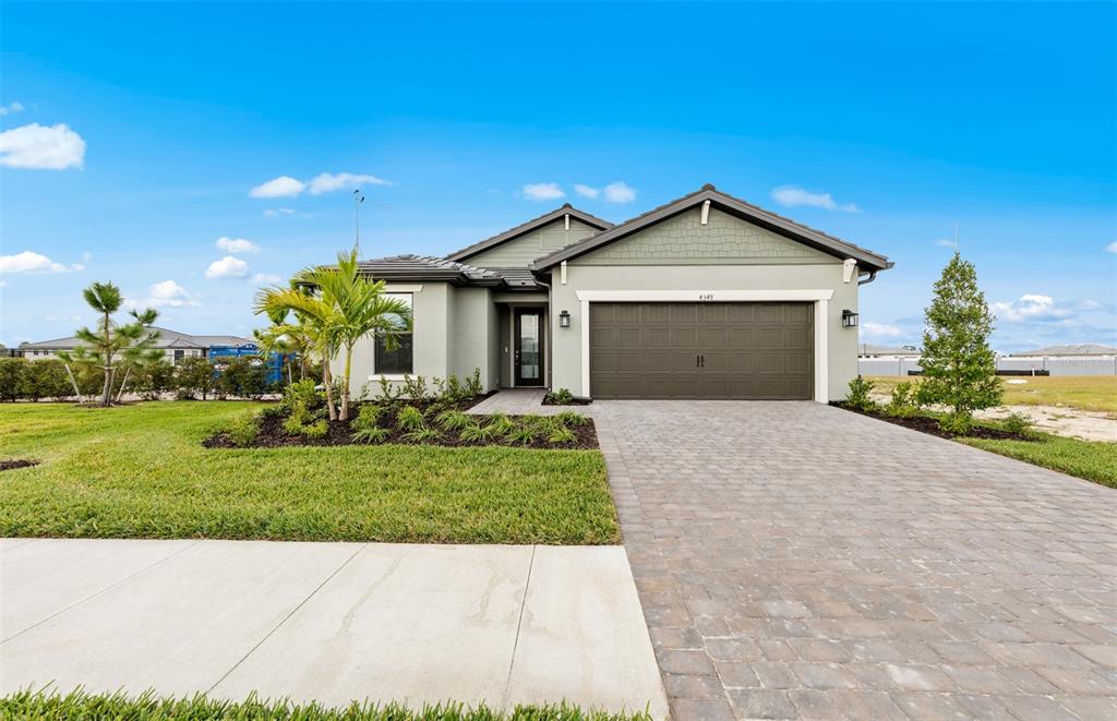 A single-story house with a paved driveway, a two-car garage, and a landscaped front yard — 4415 LAKESIDE GROVE, NORTH PORT, FL