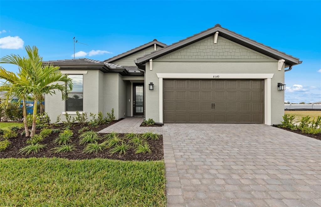A single-story house with a gray stucco exterior, a brown garage door, and a paved driveway — 4415 LAKESIDE GROVE, NORTH PORT, FL