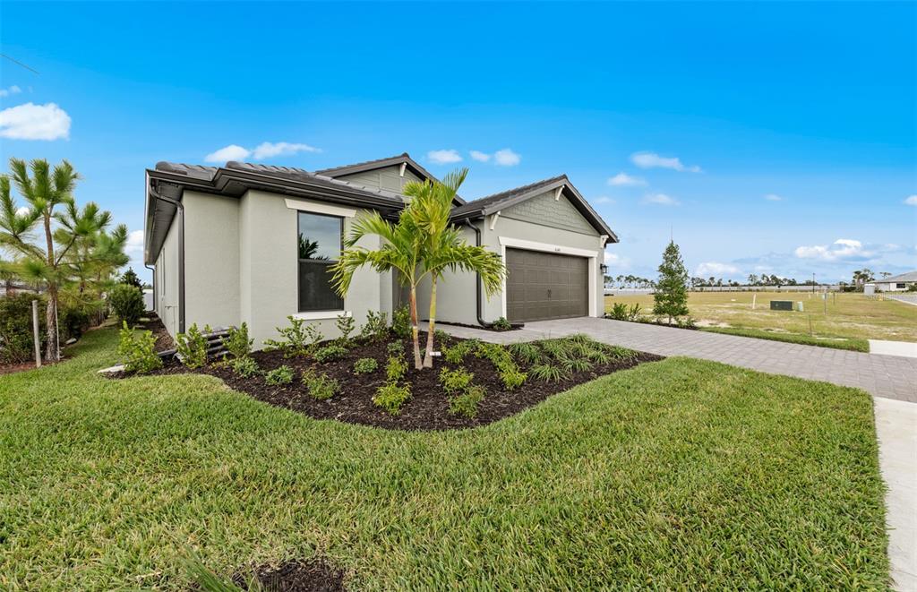 A single-story house with a gray exterior, a two-car garage, and a landscaped front yard — 4415 LAKESIDE GROVE, NORTH PORT, FL