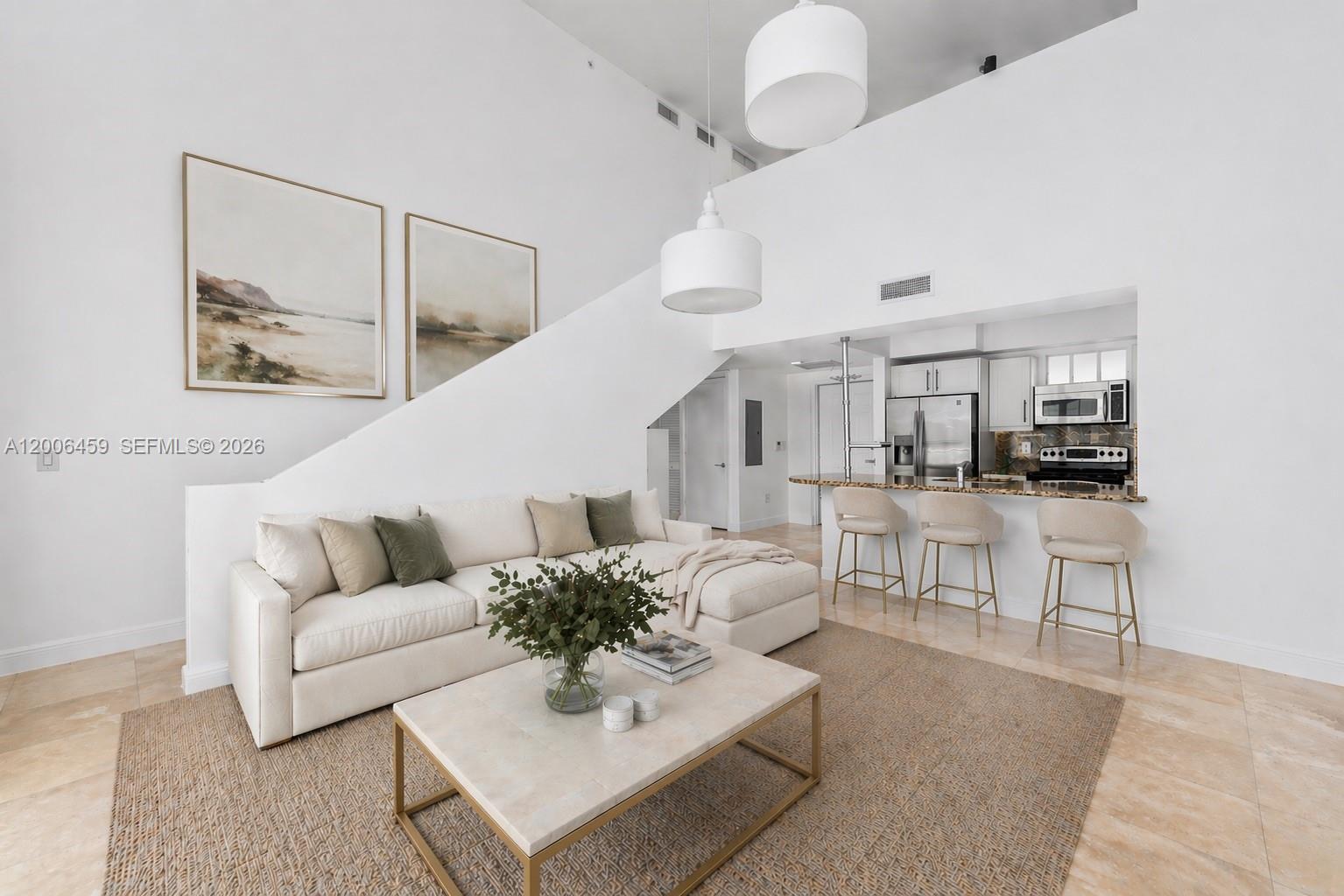 A living room with a white sectional sofa, coffee table, and an open kitchen area — 7270 SW 88th St # B519, Miami FL 33156, MIAMI, FL