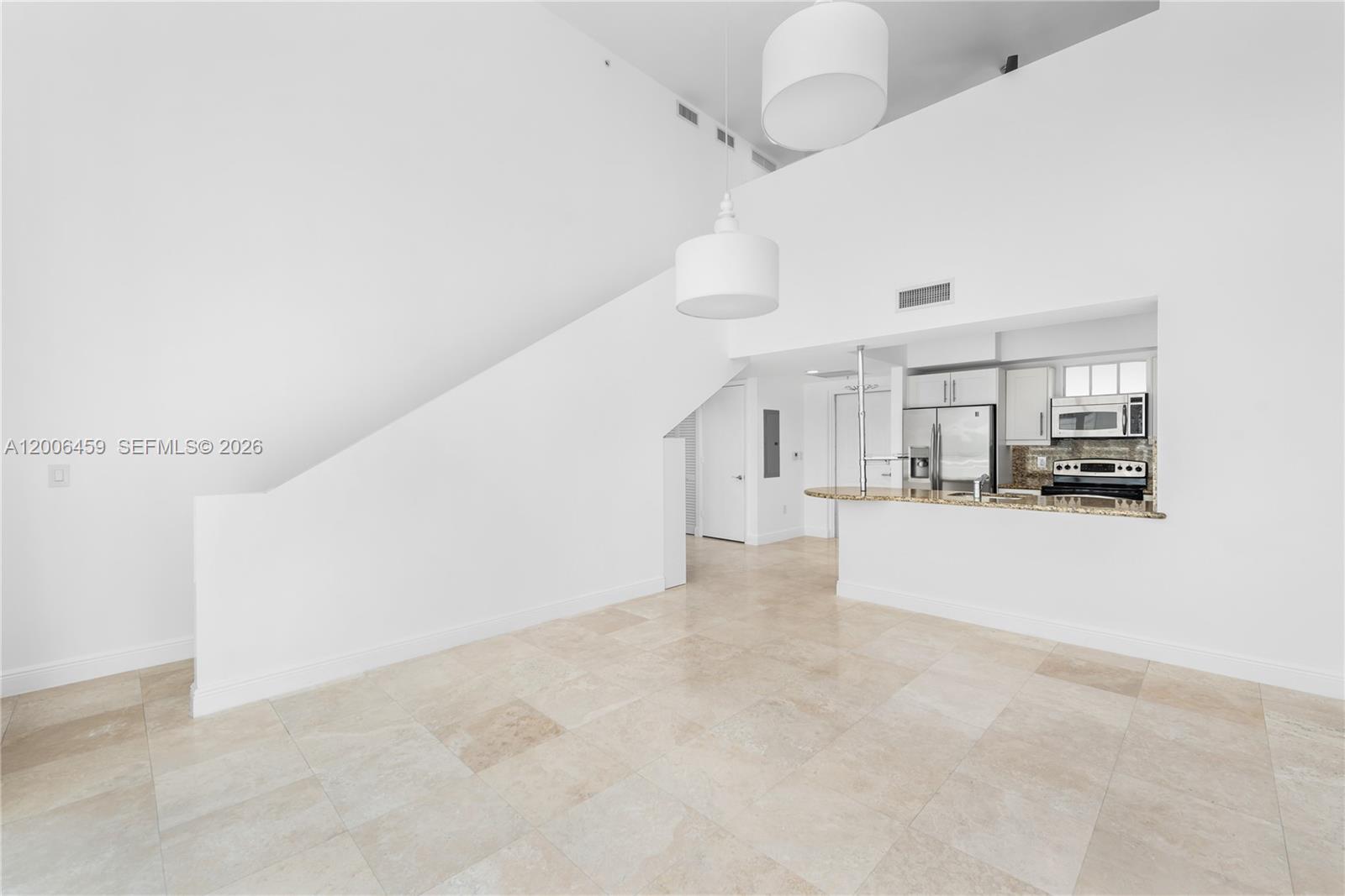 A bright, open-plan living area features white walls, tile flooring, and a pass-through kitchen — 7270 SW 88th St # B519, Miami FL 33156, MIAMI, FL