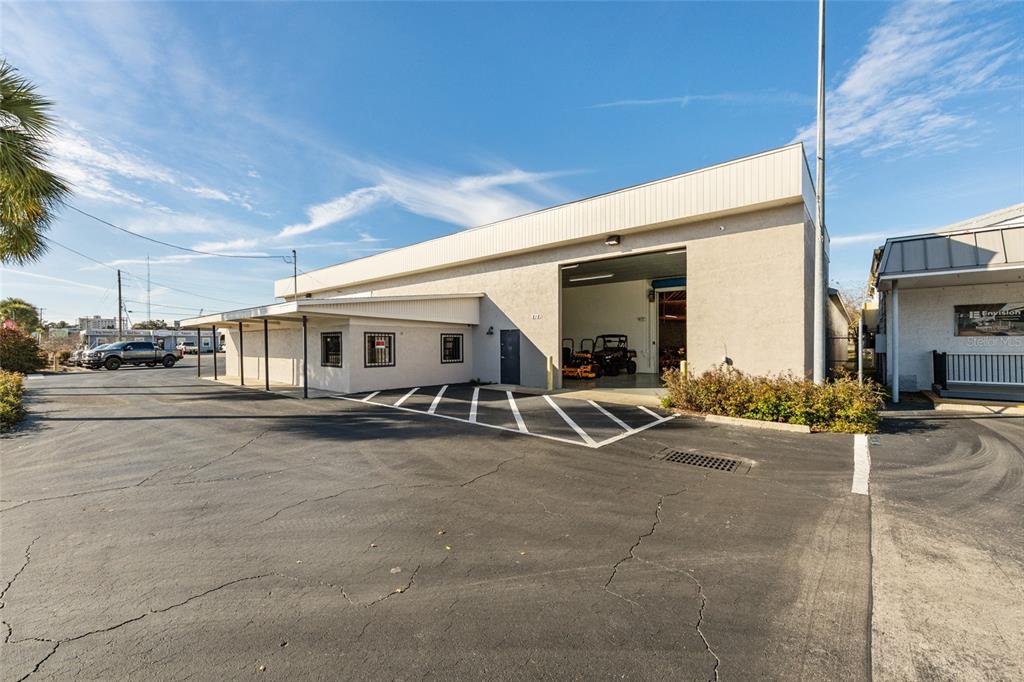 A commercial building with a large open bay, a covered walkway, and an asphalt parking lot — 818 NORTH MAGNOLIA AVE, OCALA, FL