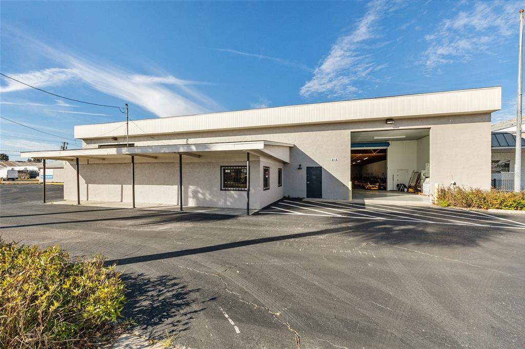A commercial building with a covered walkway, a large bay door, and an asphalt parking lot — 818 NORTH MAGNOLIA AVE, OCALA, FL
