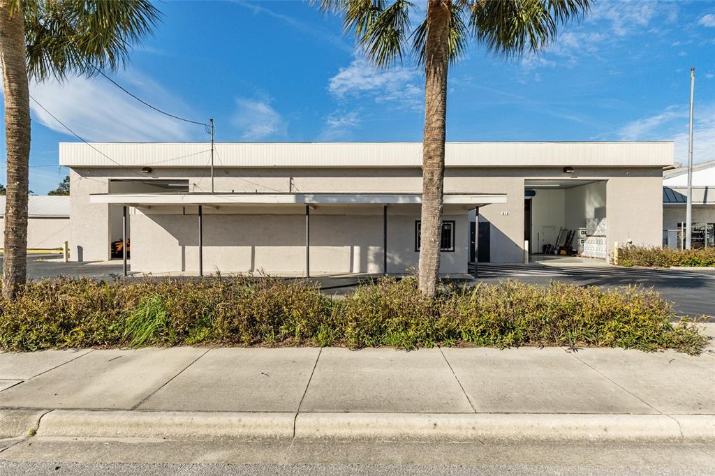 A single-story commercial building with two garage bays and a covered walkway under palm trees — 818 NORTH MAGNOLIA AVE, OCALA, FL