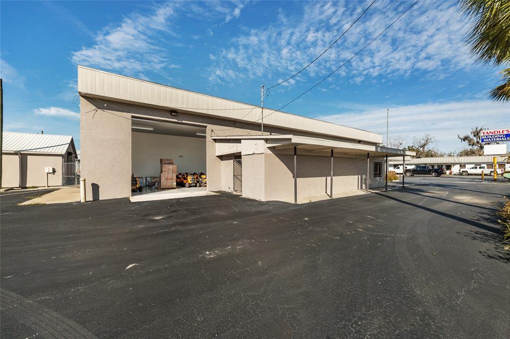 A commercial building with a large open bay, a covered walkway, and asphalt parking — 818 NORTH MAGNOLIA AVE, OCALA, FL