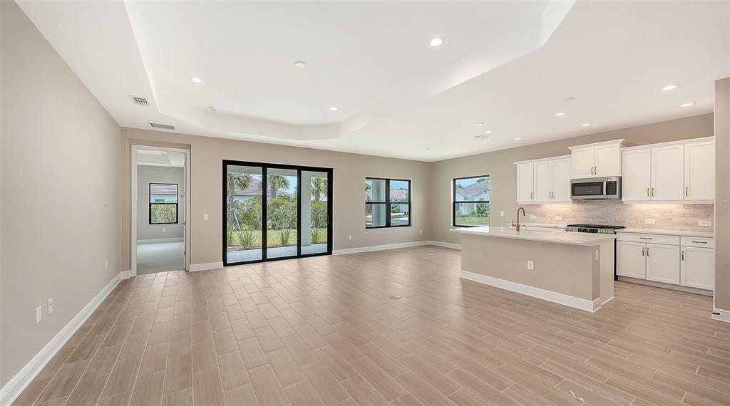 An open-concept living area with tile floors, a kitchen island, and sliding glass patio doors — 6568 BIG BAYOU DRIVE, SARASOTA, FL