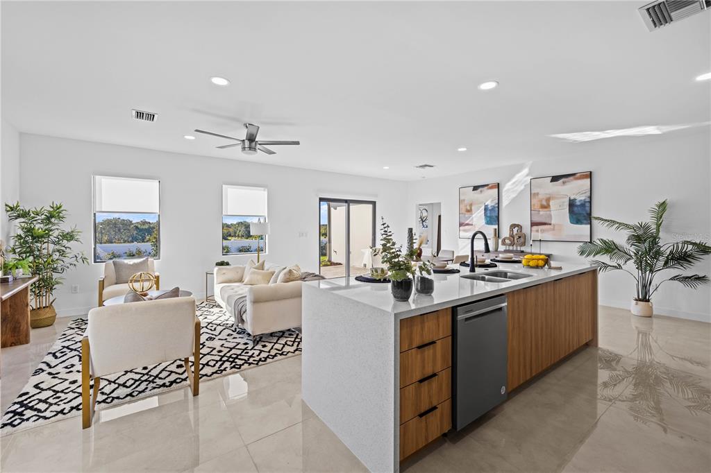 A modern open-concept kitchen and living area featuring a large waterfall island and tile flooring — 6440 QUARTET STREET, MASCOTTE, FL