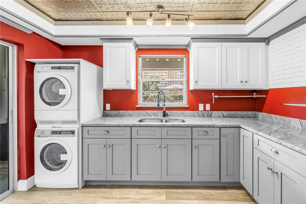 A kitchen with gray cabinets, granite countertops, a stacked washer-dryer, and red walls — 4455 DUHME ROAD UNIT 109, ST PETERSBURG, FL