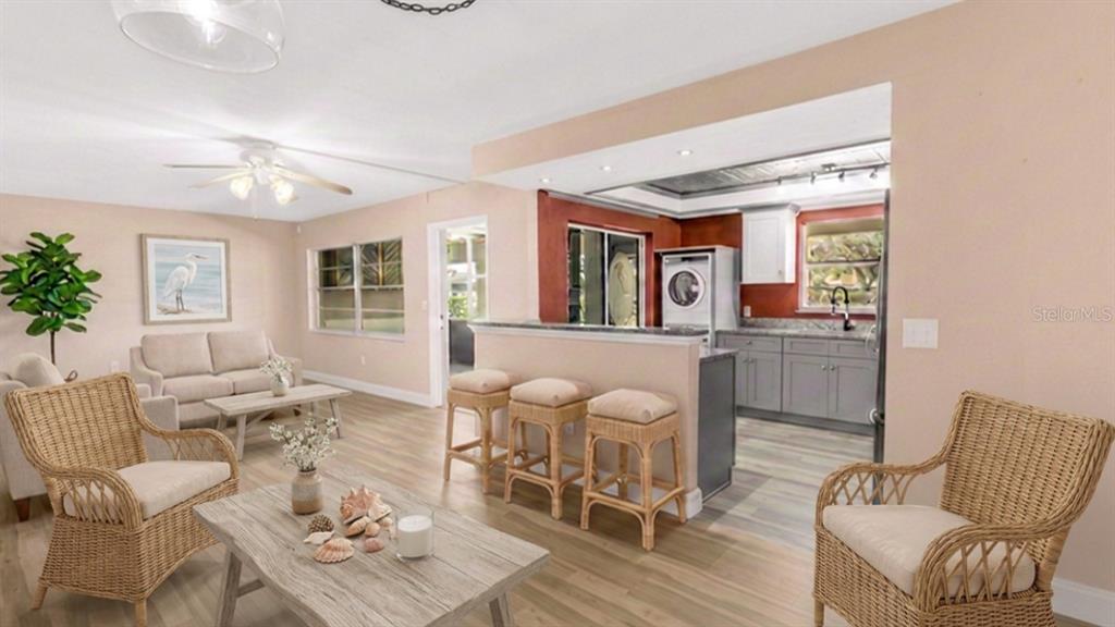 A living room with wicker furniture opens to a kitchen featuring a breakfast bar — 4455 DUHME ROAD UNIT 109, ST PETERSBURG, FL